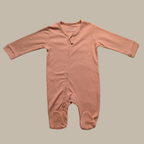 A long-sleeve baby footed sleeper in a dusty rose pink cotton