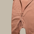 Close-up of a ribbed cotton baby jumpsuit in a dusty rose pink colour, showing the front zipper closure and leg openings