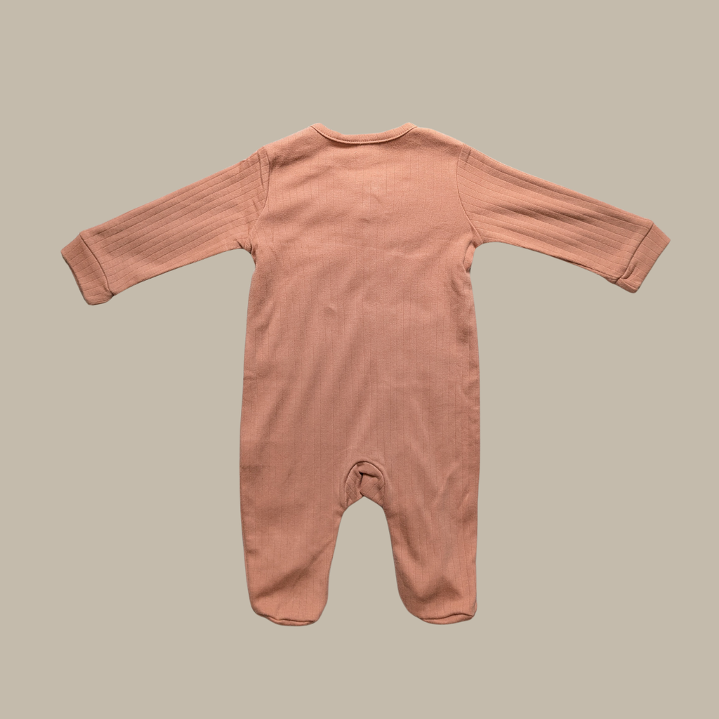 A long-sleeve footed romper in a dusty rose colour made of cotton