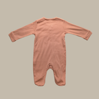 A long-sleeve footed romper in a dusty rose colour made of cotton