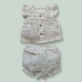 Baby outfit set with top and shorts on a light green background