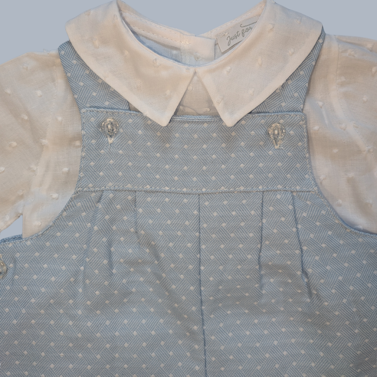 Vintage baby dungarees
 with polka dot pattern and cream collar on a light gray background