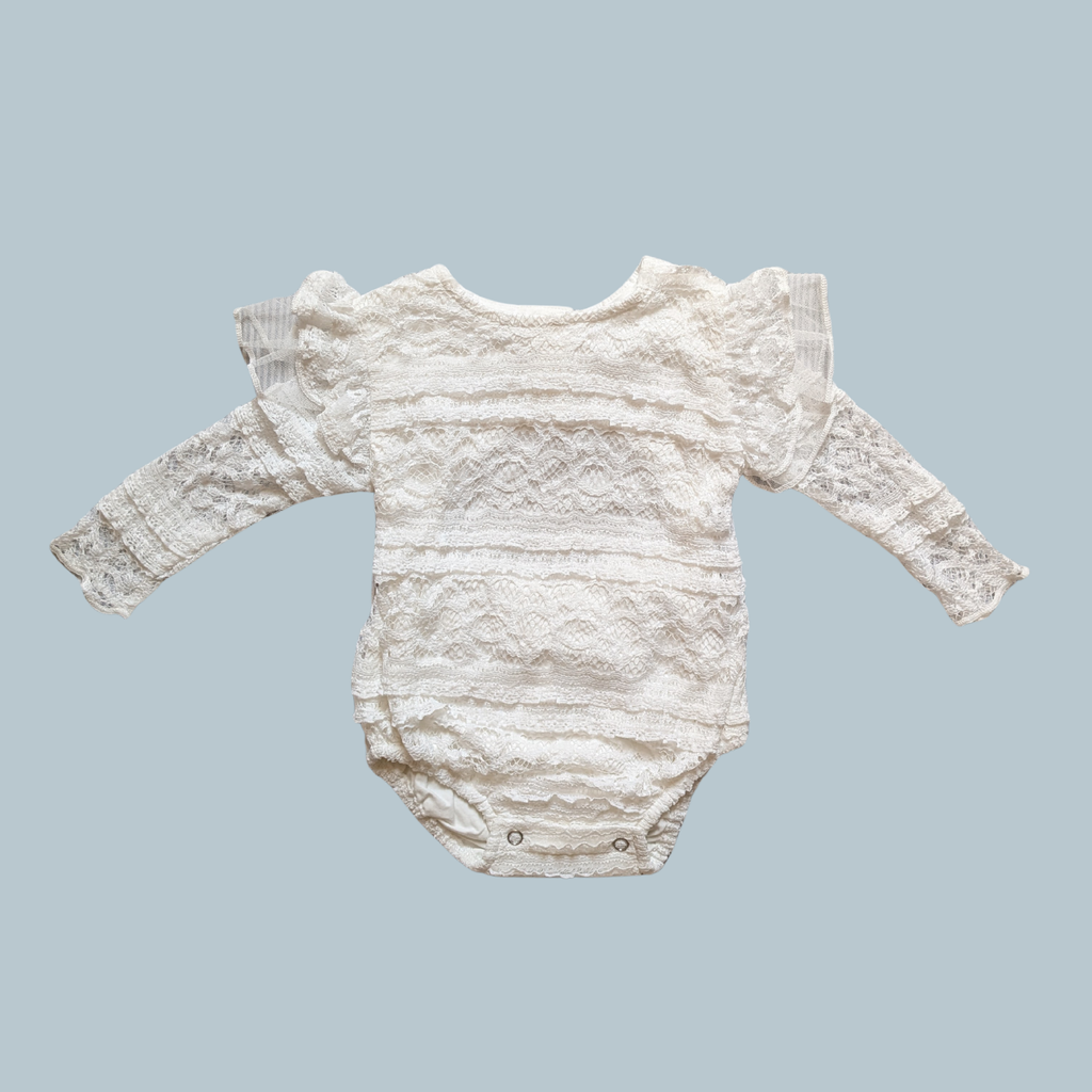 A white lace baby bodysuit with long sleeves and ruffled shoulders