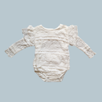 A white lace baby bodysuit with long sleeves and ruffled shoulders