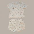 Children's outfit with patterned shirt and shorts on a beige background