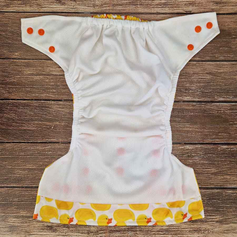 White diaper with yellow duck pattern on a wooden surface