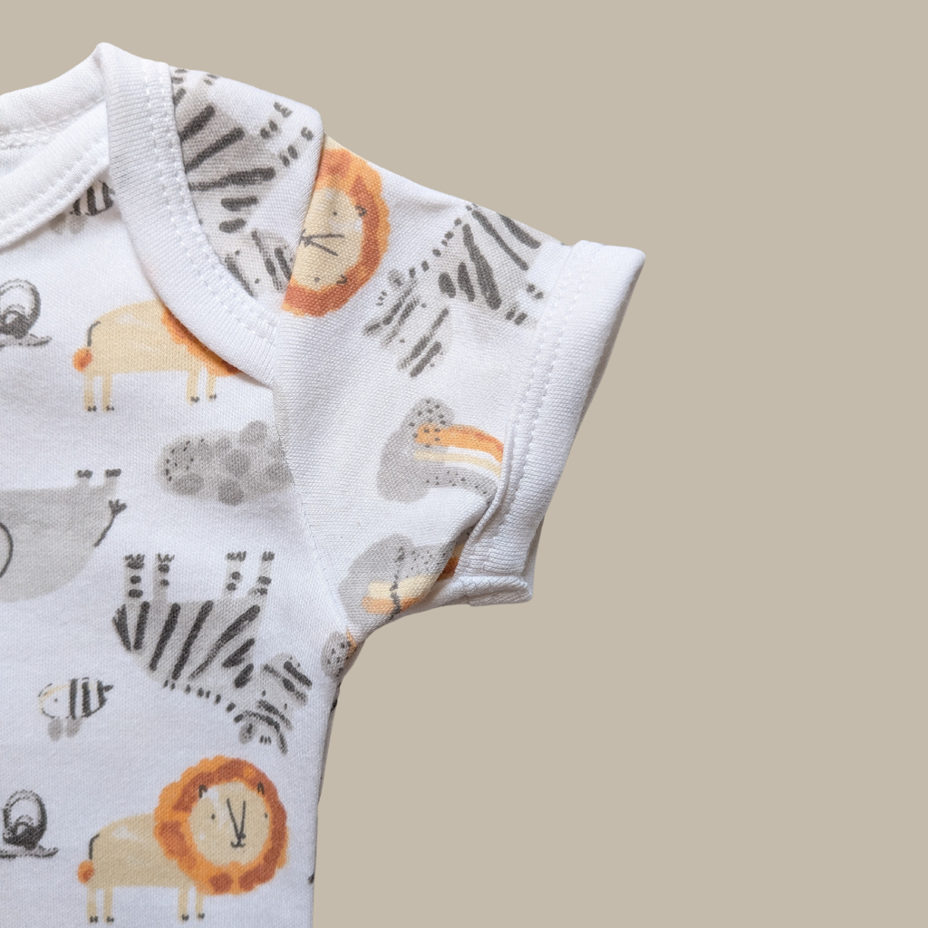 Close-up of a white short-sleeve baby bodysuit with an all-over safari animal print including a lion, zebra, insects and elephant.