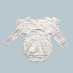 An white baby romper with long lace sleeves, ruffled lace detailing, and a buttoned neckline