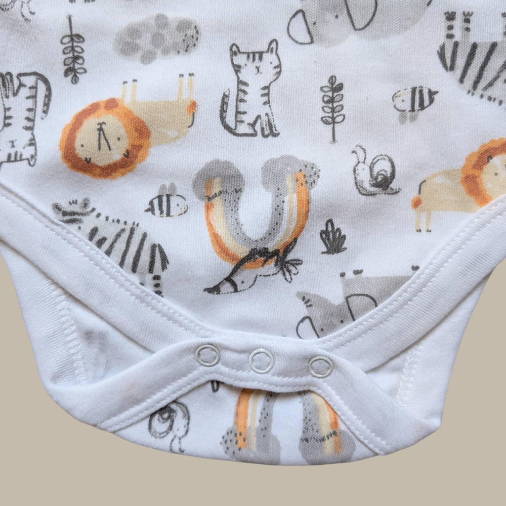 Close-up of a baby bodysuit with a white base and an all-over safari animal print including zebra, lion, insect, and bird motifs in grey, black, orange, and beige showing popper closure.