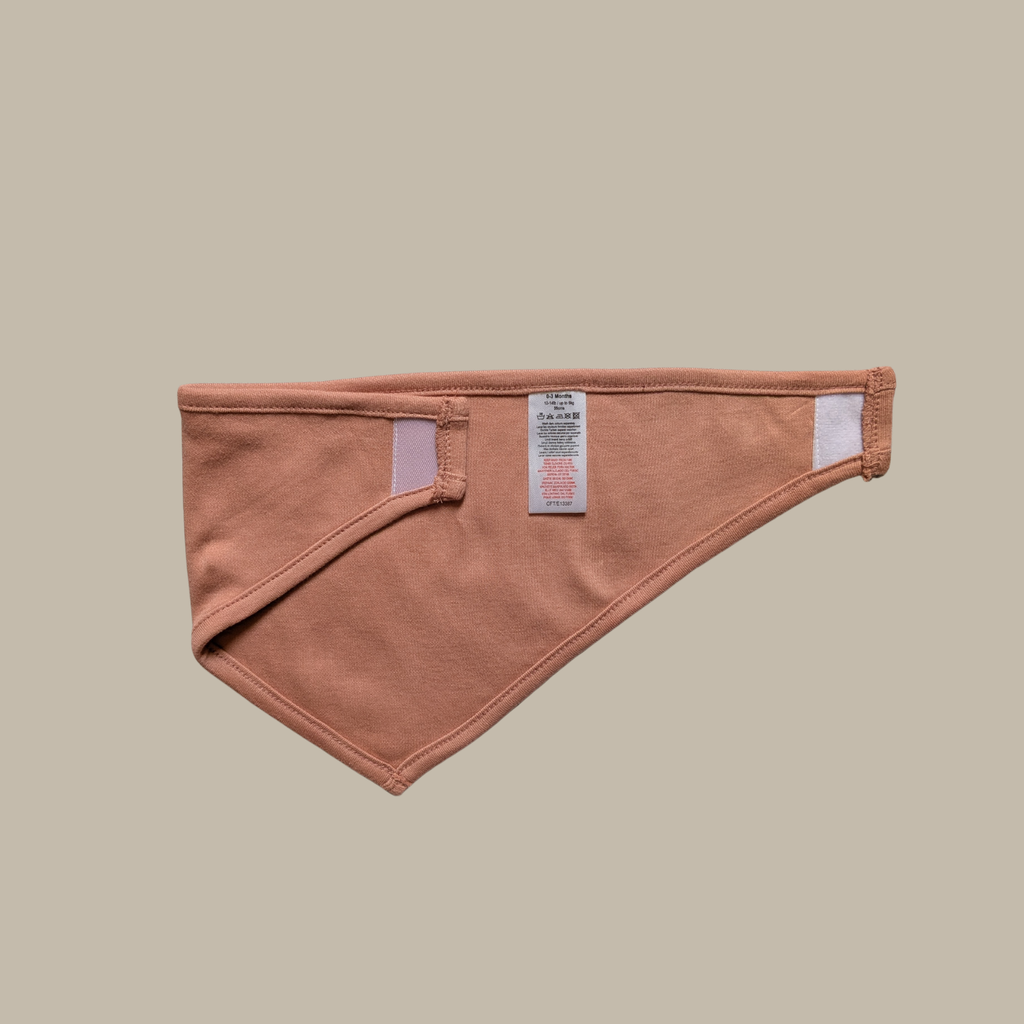 A terracotta-coloured triangular bib with velcro fastening
